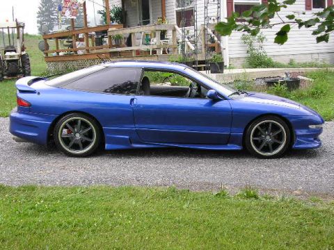 1994 Ford Probe - A blue 1994 Ford Probe is parked on a gravel driveway in front of a house.