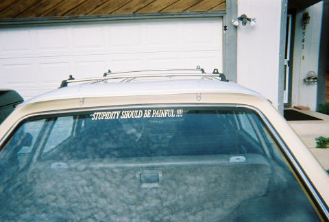 1972 Ford Ranchero - A station wagon is parked in front of a garage door, displaying a humorous sticker on its rear window.