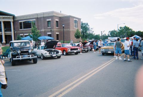 1972 Ford Ranchero - A car show displays several vintage vehicles parked along a street in front of a brick building.