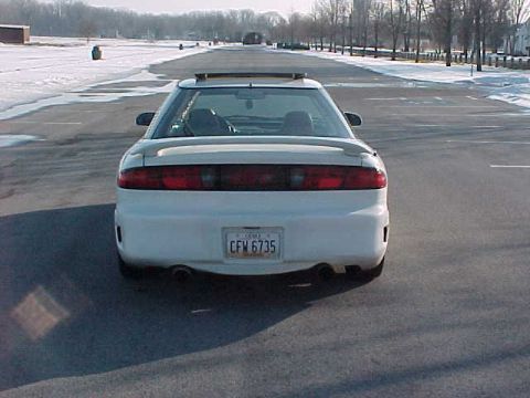 1993 Ford Probe - A white coupe is parked on an empty road with snow on the sides.