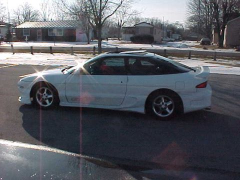 1993 Ford Probe - A white 1993 Ford Probe is parked on a street with houses in the background.