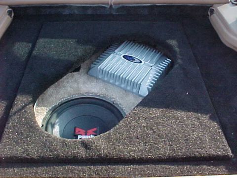 1993 Ford Probe - A car's trunk houses a custom-mounted subwoofer and amplifier, aftermarket audio equipment.
