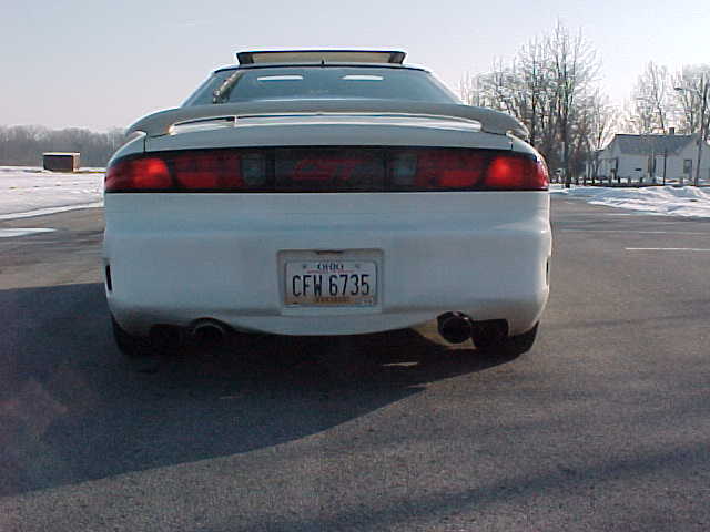 Rear of white sports car with spoiler and dual exhaust pipes. Ohio license plate CFW 6735 visible