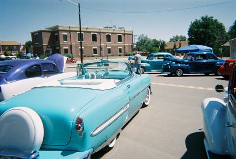 1972 Ford Ranchero - Several classic cars are parked on a street, including a light blue convertible in the foreground.