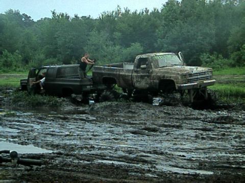 1987 Suzuki Samurai - Two vehicles are stuck in a muddy field, with people trying to get them out.