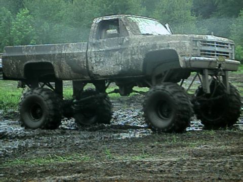 1987 Suzuki Samurai - This lifted pickup truck is heavily covered in mud, suggesting it has been used for off-roading or mud bogging.