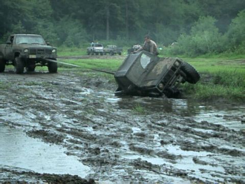 1987 Suzuki Samurai - Two off-road vehicles are stuck in deep mud, with one being pulled by the other.