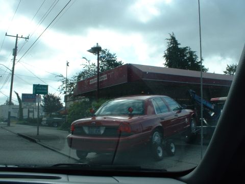 1999 Ford Crown Victoria - A red sedan, likely a 1998 Ford Crown Victoria, is being towed on a flatbed truck.