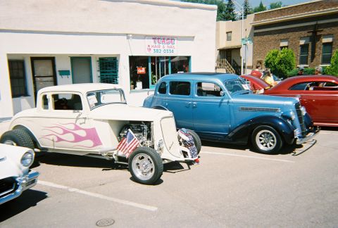 1972 Ford Ranchero - Two classic cars are parked outside a building with a sign for 'Tease Hair & Nail'.