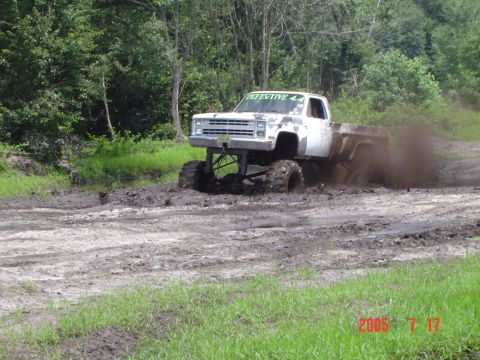 1995 Dodge 1500 - A lifted pickup truck navigates a muddy track, kicking up dirt and spray.