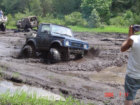 1995 Dodge 1500 - An off-road vehicle navigates a muddy track, with another vehicle visible in the background.
