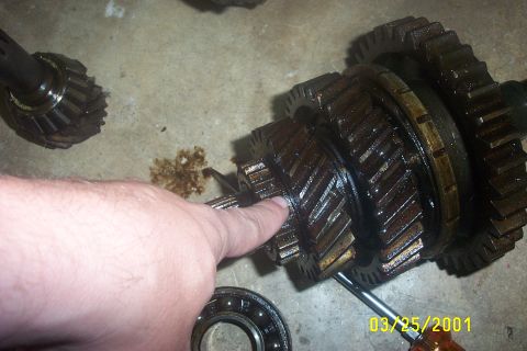 1979 Ford F-150 - Close-up of transmission gears and a bearing, with a hand pointing to the gears. Oil is visible on the floor.