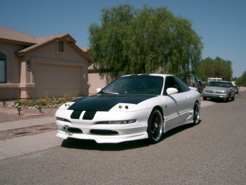 1996 Ford Probe - A white 1996 Ford Probe with a black hood and racing stripes is parked in front of a house.