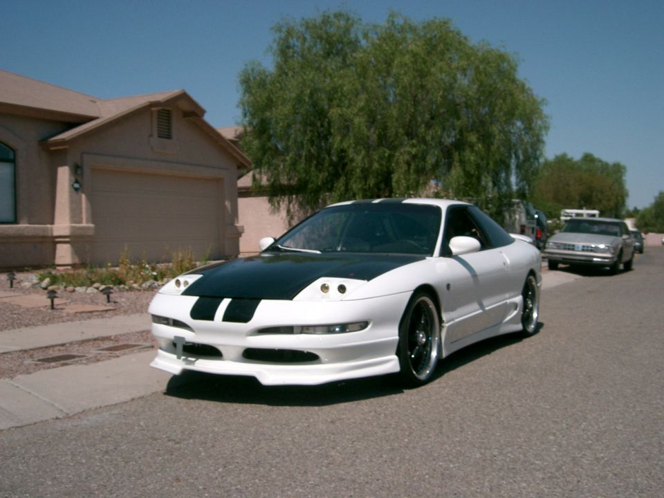 White 1996 Ford Probe with black hood stripes parked on a residential street
