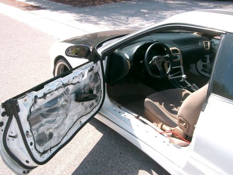 1996 Ford Probe - The interior of a white car is visible with the driver's door open, revealing the dashboard, steering wheel, and seats.
