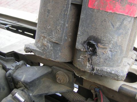1995 Ford Bronco - Close-up of a damaged engine component with a hole melted through it and a red sticker visible.