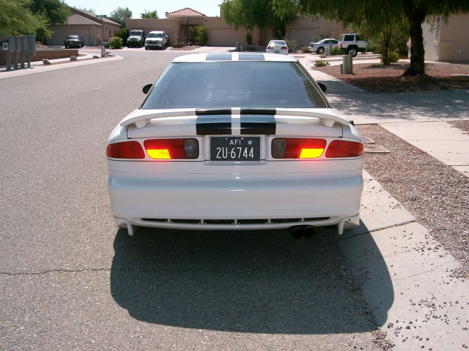 Rear view of a white 1996 Ford Probe with black racing stripes on the trunk and roof
