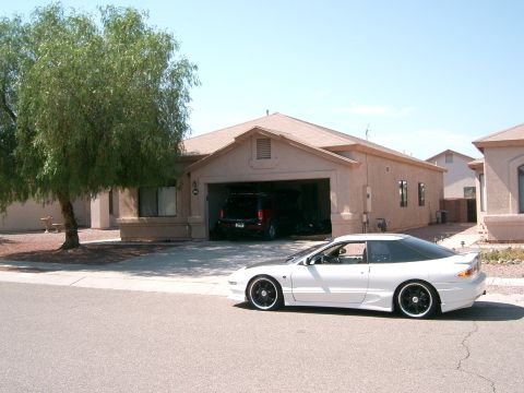 1996 Ford Probe - A white 1996 Ford Probe is parked in front of a suburban house with a garage containing another vehicle.