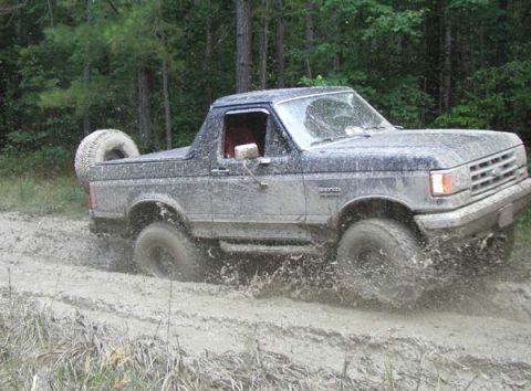 1988 Ford Bronco - This 1987 Ford Bronco navigates a muddy trail, kicking up spray as it goes.