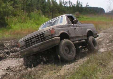 1988 Ford Bronco - Muddy Ford Bronco navigating a difficult off-road terrain.