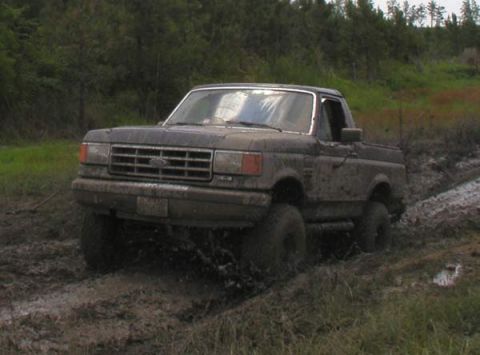 1988 Ford Bronco - Mud-covered 1987-1991 Ford Bronco driving through deep mud.