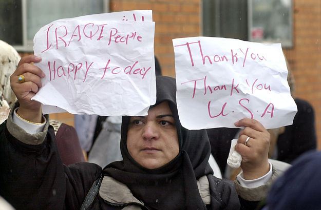 Woman holding two signs, one reading 'IRAQI People Happy today' and the other 'Thank You Thank You U.S.A.'