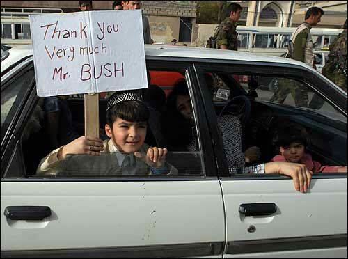 White sedan side view with children inside holding a sign that says "Thank You Very Much Mr. BUSH"