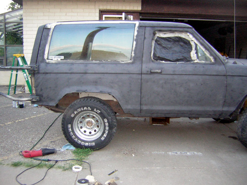 1986 Ford Bronco II body in primer, side view, with windows covered and some tools nearby