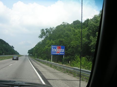 1993 Ford Taurus - A car drives on a highway past a welcome sign for Indiana, the Crossroads of America.