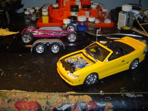 1979 Ford Bronco - Model car parts and supplies are laid out on a workbench, with two model vehicles visible.