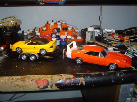 1979 Ford Bronco - Workbench cluttered with model car parts, paint, and two completed model cars.