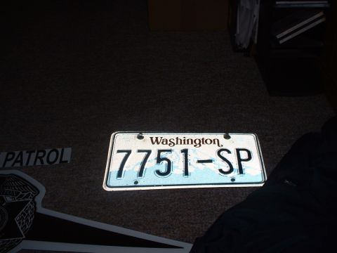 1999 Ford Crown Victoria - A Washington state license plate and a police decal are shown on a dark surface.