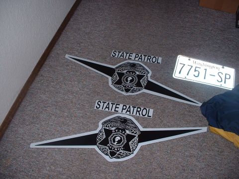 1999 Ford Crown Victoria - Decals and a license plate for Washington State Patrol are laid out on a carpeted surface.