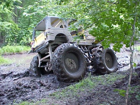1987 Suzuki Samurai - This heavily modified off-road vehicle is deeply stuck in a muddy trail.