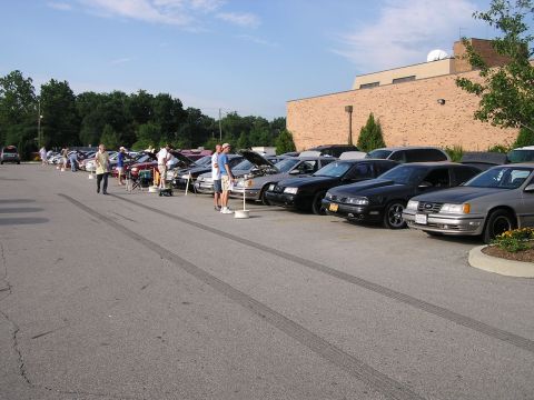 1993 Ford Taurus - A line of cars, including a silver 1993 Ford Taurus, are parked in a lot during a car show.