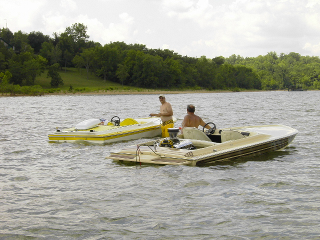 Yellow jet boat and white bowrider floating side by side on a lake