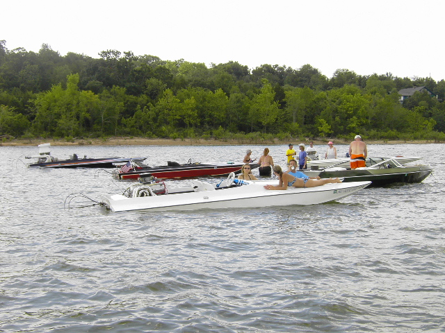 Open-bow boats rafted together on a lake with people lounging on deck