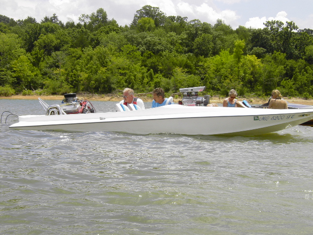 White boat with a powerful engine and people on a lake