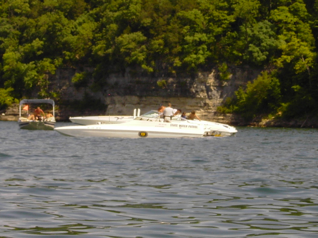 White State Water Patrol powerboat with gold shield decal on a lake below a bluff