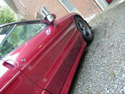 1994 Ford Probe - Side view of a red car's door and fender, parked on a gravel surface.