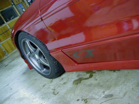 1994 Ford Probe - Side view of a red car, showing a GT badge on the lower body panel and a five-spoke wheel.