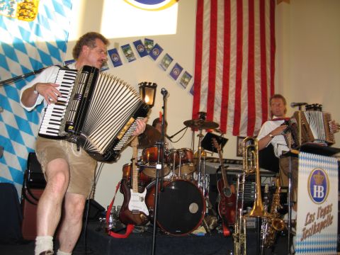 2003 BMW Z4 - A band performs with accordions, drums, and brass instruments, set against a backdrop of American and Bavarian flags.