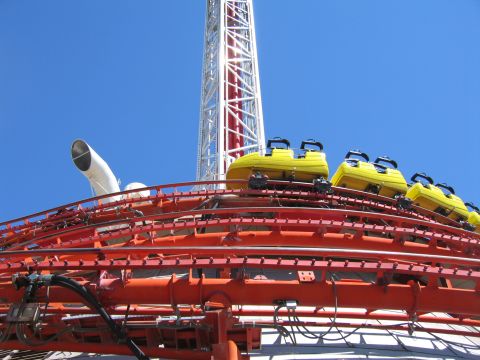 2003 BMW Z4 - A roller coaster with yellow cars ascends a track, with a tall tower visible against the clear blue sky.