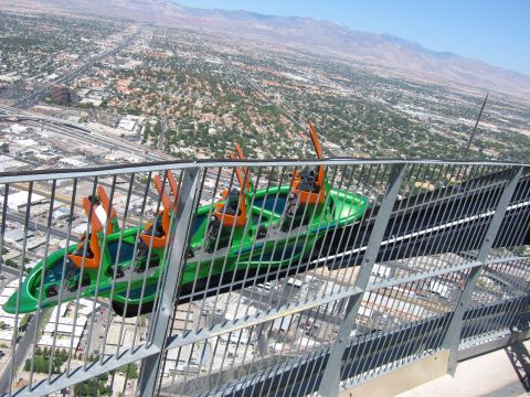 2003 BMW Z4 - A roller coaster car ascends a track, offering a panoramic view of the city below.