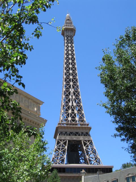 2003 BMW Z4 - A replica of the Eiffel Tower stands tall against a clear blue sky, framed by green trees.
