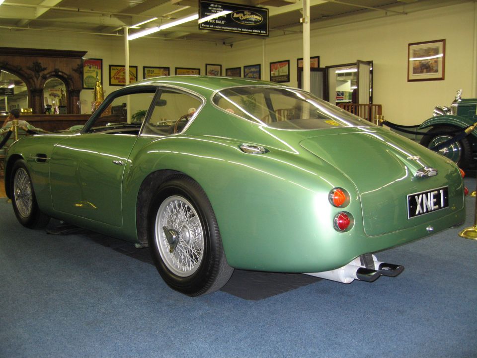 Green classic coupe with wire wheels and dual exhaust pipes. License plate reads XNE 1
