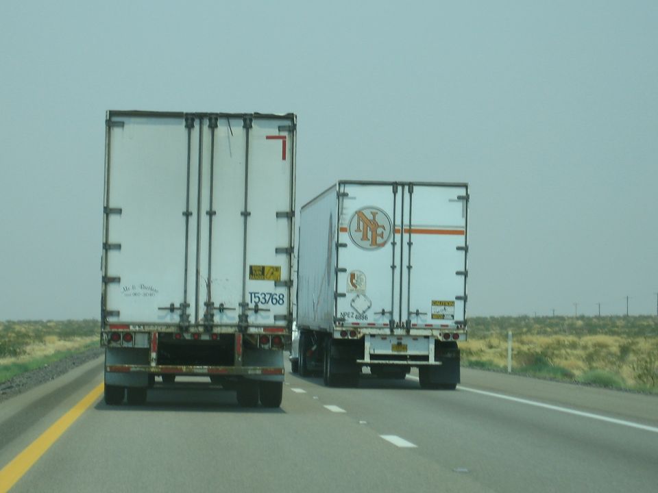 Rear view of two semi-trailer trucks on a highway