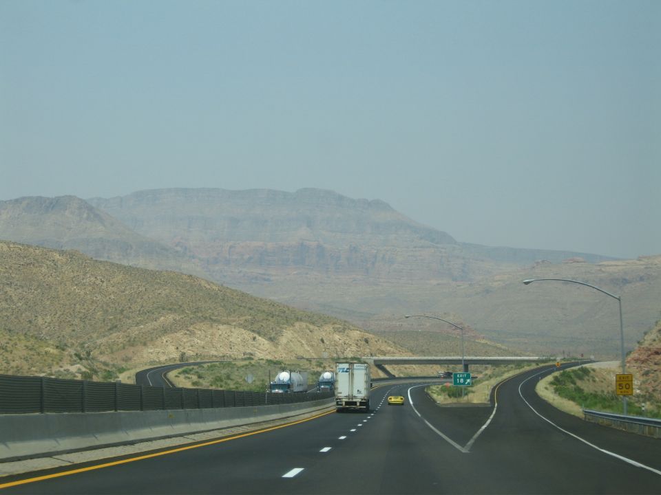 Yellow sports car on a highway with mountains in the background