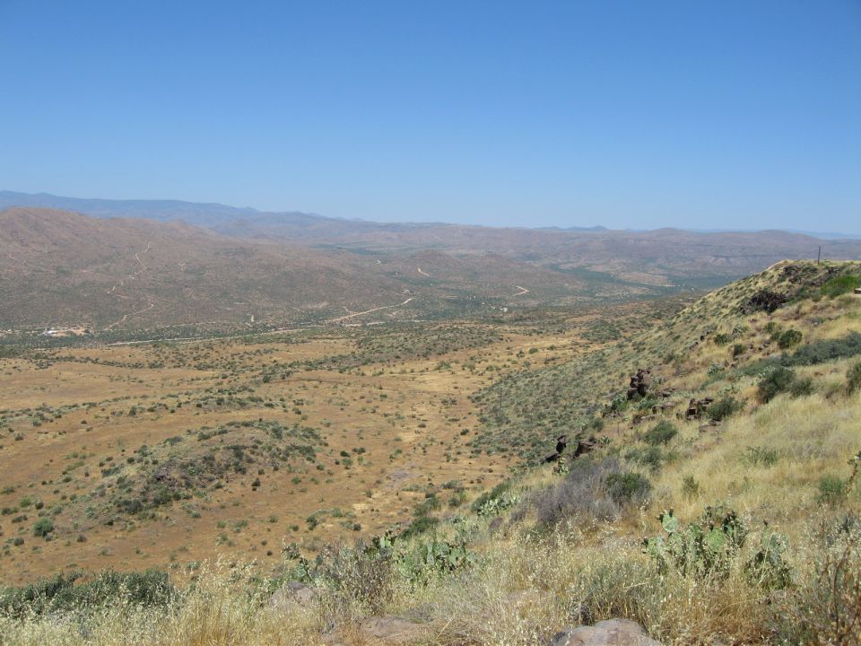 Desert landscape with mountains and a winding road, Supermotors logo visible