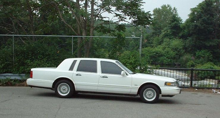 White 1997 Ford Crown Victoria sedan parked on asphalt, side view